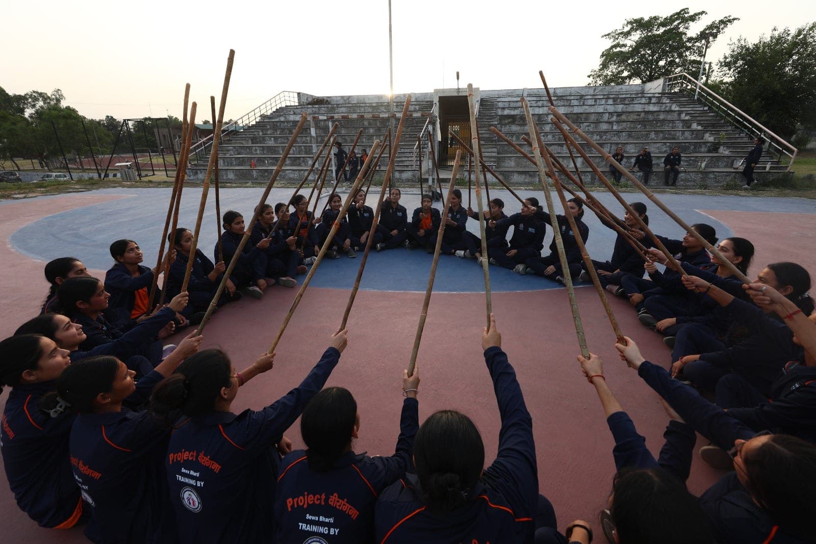Women recruits raise lathis together in a self-defence training circle at Project Virangana, Shakti Udghosh Foundation.