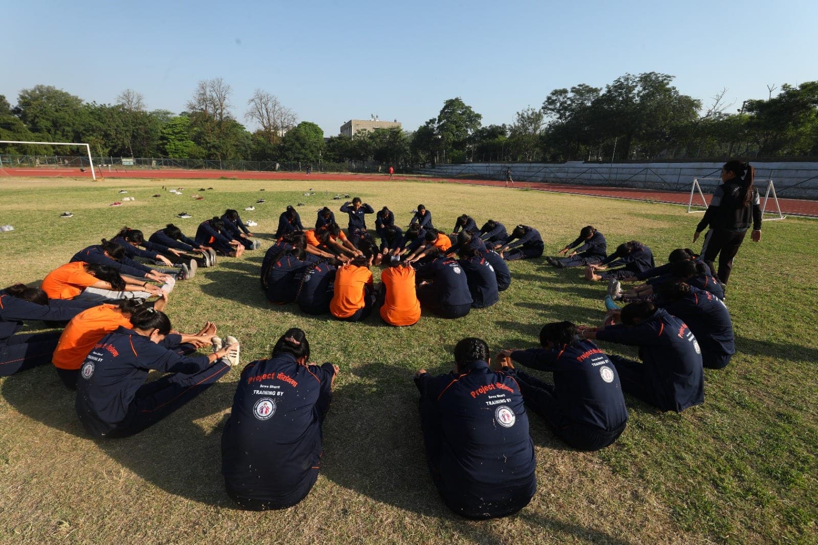 Women recruits sit in a large circle for cool-down stretches at a Project Virangana training camp, Shakti Udghosh Foundation.
