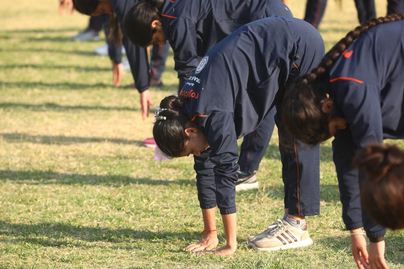 A woman recruit touches the ground in a forward bend during a morning flexibility routine, Shakti Udghosh Foundation.
